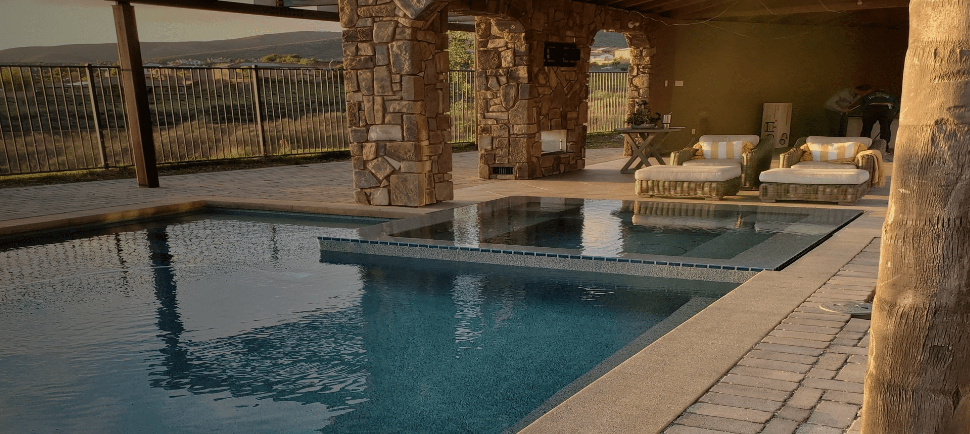 A luxurious stone patio with a pool and outdoor seating area.